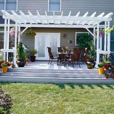 a white pergolan sitting on top of a patio next to potted plants