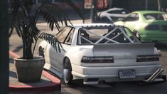 a white car parked on the side of a road next to a palm tree and potted plant