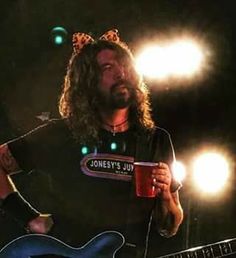 a man with long hair holding a blue guitar and wearing a crown on his head