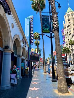 the hollywood walk of fame is lined with shops and palm trees on a sunny day