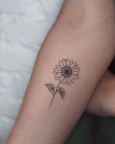 a small sunflower tattoo on the left arm and right leg, with one flower in it's center