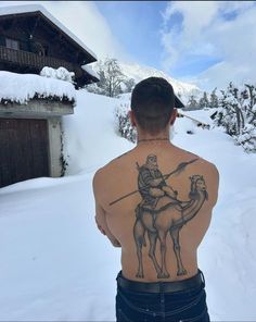 a man with a tattoo on his back standing in the snow