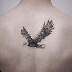 an eagle tattoo on the back of a man's upper body is shown in black and white