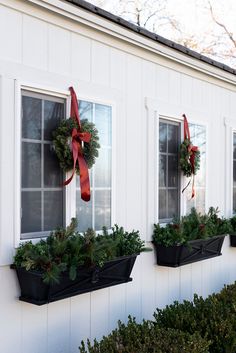 three planters with wreaths on them are hanging from the side of a house