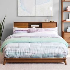 a bed sitting in a bedroom next to a wooden shelf filled with books and plants