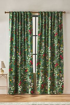 a green floral curtain with red and yellow flowers on it in front of a window