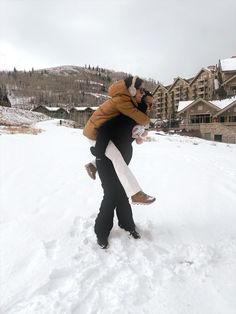 two people walking in the snow carrying each other