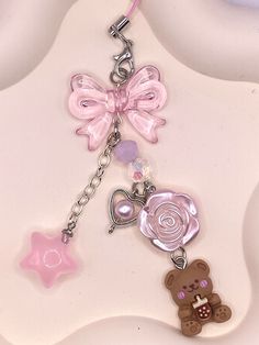 a pink teddy bear keychain with charms attached to it