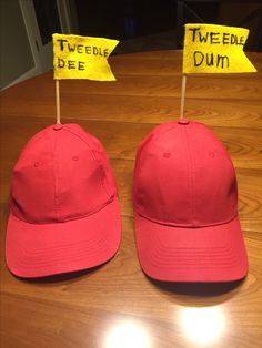 two red hats with yellow signs on them sitting on top of a wooden table next to each other