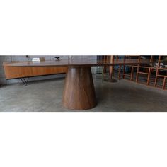 a large wooden table sitting on top of a cement floor next to a book shelf