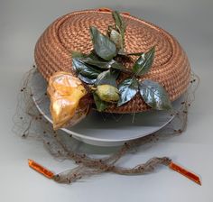 This 1950's vintage, brown straw, pill box hat is quite lovely.  The brown straw body of the hat is in like new condition.  The adorning large fabric flower is yellow-pink-beige in color and has faded and aged with time.  The hat has green fabric leaves and a lovely brown netting that can be elegantly wrapped around face or head adding a touch of class to your look.  The two ends of the netting have orange velvet fabric ends.  Made by the milliner; "Tori of California at Best Appeal (from Seattl Pill Box Hat, Fabric Leaves, Box Hat, Orange Velvet, Pillbox Hat, Bohemian Look, Fabric Flower, Touch Of Class, Pink Beige