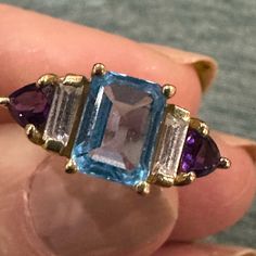 14 Karat Yellow Gold Ring With Rectangular Blue Topaz Centerstone. Bezel Cut Cz On Either Side Of The Blue Topaz With Trilliant Cut Amethyst On The Outside. Sits Up So Light Can Go Underneath The Stones And Illuminate The Ring With Natural Light. All Stones In Great Shape And Firmly Set. Approximate Ring Size Is A Six.. Blue Sapphire Multi-stone Baguette Ring, Blue Sapphire Ring With Multi-stone Baguette Cut, Blue Multi-stone Baguette Cut Sapphire Ring, Formal Blue Multi-stone Gemstones, Blue Emerald Cut Jewelry With Gemstone Accents, Blue Emerald-cut Jewelry With Gemstone Accents, Blue Multi-stone Aquamarine Jewelry, Blue Aquamarine Multi-stone Jewelry, Formal Emerald Cut Multi-stone Topaz Ring