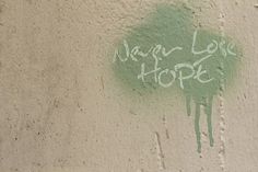 graffiti written on the side of a wall that says never love hope with green paint