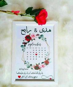 a red rose sitting on top of a table next to a calendar with arabic writing