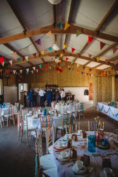 tables and chairs are set up for an event with colorful flags hanging from the ceiling