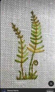 two green plants are embroidered onto a white piece of cloth