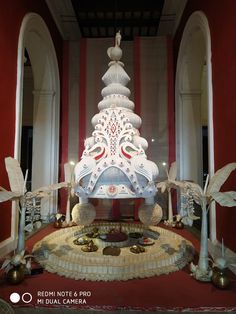 a large white christmas tree sitting in the middle of a room with red and white walls