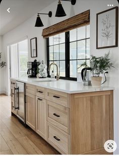 a large kitchen with wooden cabinets and white counter tops, along with black framed windows