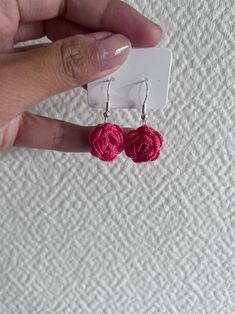 a pair of pink crochet flower earrings in the shape of roses on a white background