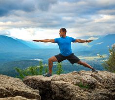 a man doing yoga on top of a mountain