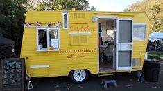 a yellow food truck is parked on the side of the road with its door open