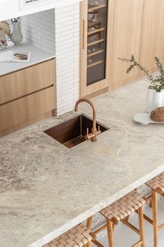 a kitchen counter with a sink and wooden chairs