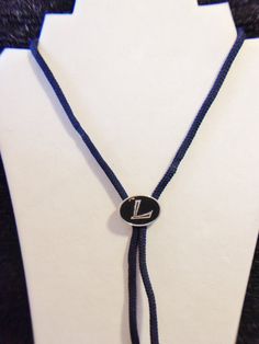 Letter L bolo tie. The slide measures approx. 1-1/4 inch long x just under an inch wide. The slide is a oval shaped. Black and silver. It has a blue fabric cords and metal silver tone aglets. Add it to your collection. Pre owned. The slide has fading to the black paint. All sales are final and as is. Thank you for looking. You may also love this: https://www.etsy.com/listing/616565166/initial-r-bolo-tie-mens-fashion?ga_search_query=bolo&ref=shop_items_search_4 Blue Lariat Bolo Tie For Gift, Bolo Tie Men, Ties Mens Fashion, Bolo Ties, Tie Men's, Fabric Letters, Letter L, Bolo Tie, Tie Accessories