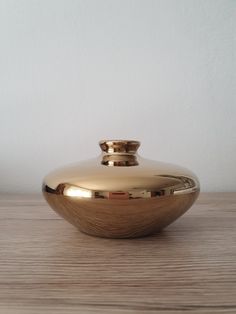 a gold vase sitting on top of a wooden table