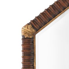 a mirror that is sitting on top of a wooden frame with a gold leaf decoration