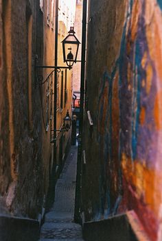 an alleyway with graffiti on the walls and a street light hanging over it's doorway