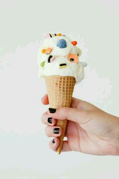 a hand holding an ice cream cone with sprinkles