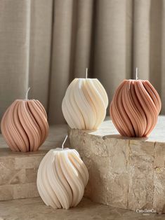 three decorative candles sitting on top of a stone slab