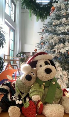 two teddy bears sitting next to each other in front of a christmas tree