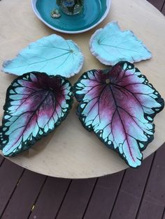 three leaf shaped plates sitting on top of a wooden table