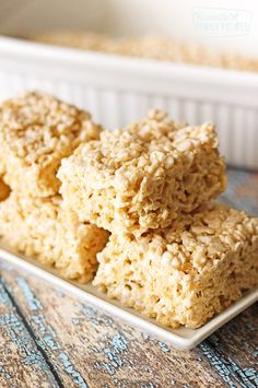 rice krispie treats stacked on top of each other in front of a white dish