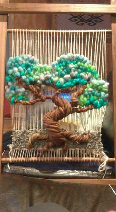 a small tree made out of yarn in a wooden frame on top of a table