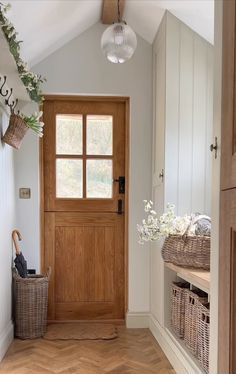 a wooden door in a white room with baskets on the floor