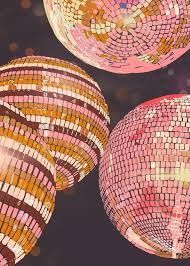 three disco balls hanging from the ceiling in front of a black background with gold and pink lights