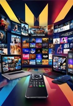 several televisions and laptops are sitting on a table in front of colorful wallpaper