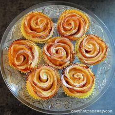 several pastries on a glass plate with icing and powdered sugar around them