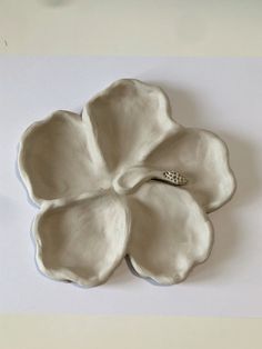 a white flower shaped dish with a diamond ring on it