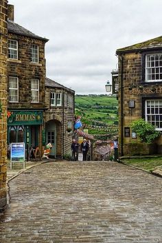 people are walking down the cobblestone street in an old town with stone buildings