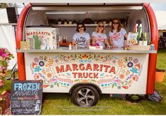 three women standing behind a food truck with the door open and decorated in bright colors