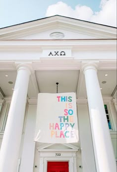 a red door is in front of a white building that says this is so happy place