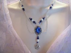 "This beautiful necklace was designed to honor the indigo children now living on this planet. They are blessed with the gift of clairvoyance and are a true blessing from the goddess. It has indigo blue Czech glass beads, pearl beads, metal chain, seed beads, sterling silver plated bead caps, pewter silver pentacle, sterling silver plated pendant with blue crystal setting and rhinestone accents. 18\" long. Toggle clasp." Mystical Blue Pendant Necklace, Magical Blue Pendant Jewelry, Handmade Gothic Blue Necklace, Handmade Blue Gothic Necklace, Blue Mystical Pendant Jewelry, Mystical Blue Pendant Jewelry, Handmade Mystical Blue Jewelry, Gothic Blue Jewelry For Gifts, Blue Gothic Jewelry For Gifts