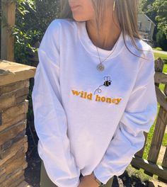 Enjoy a little wild honey with this adorable Bee Crewneck Sweatshirt. This sweatshirt features long sleeves, a crew neckline, and beautiful front embroidery. The Unisex Sizing makes the sweatshirt run slightly larger than your average sweatshirt for women. Most men find their normal size to be more snug. If you want a slightly looser fit, size up one size. Please check out our size chart for measurements to ensure an accurate fit. PLEASE BE SURE TO INPUT YOUR CORRECT SIZE/COLOR + SHIPPING ADDRES Cute Long Sleeve Sweatshirt With Text Print, Cute Sweatshirt With Text Print And Long Sleeves, Cute Crew Neck Sweatshirt With Ribbed Cuffs, Cute Crew Neck Top With Ribbed Cuffs, Cute White Tops With Ribbed Cuffs, Crew Neck Sweatshirt With Text Print For Spring, Fall Hoodie With Text Print And Crew Neck, Fall Crew Neck Hoodie With Text Print, Spring Crew Neck Hoodie With Graphic Print