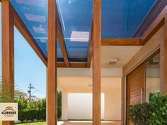 the inside of a house with wood and glass on it's roof, surrounded by greenery