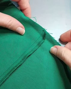 someone is cutting through the side of a green piece of fabric