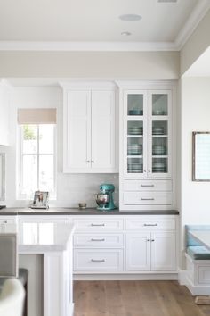 a kitchen with white cabinets and counter tops