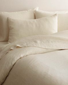 an unmade bed with white sheets and pillows